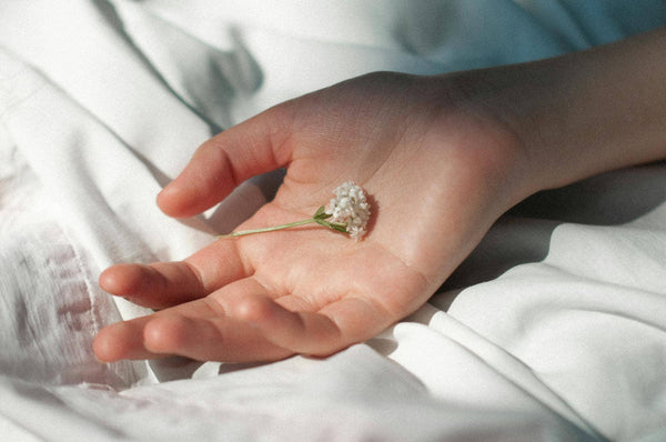 fleur dans une main sur des draps