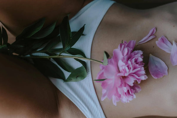 fleur rose posé sur un ventre de femme