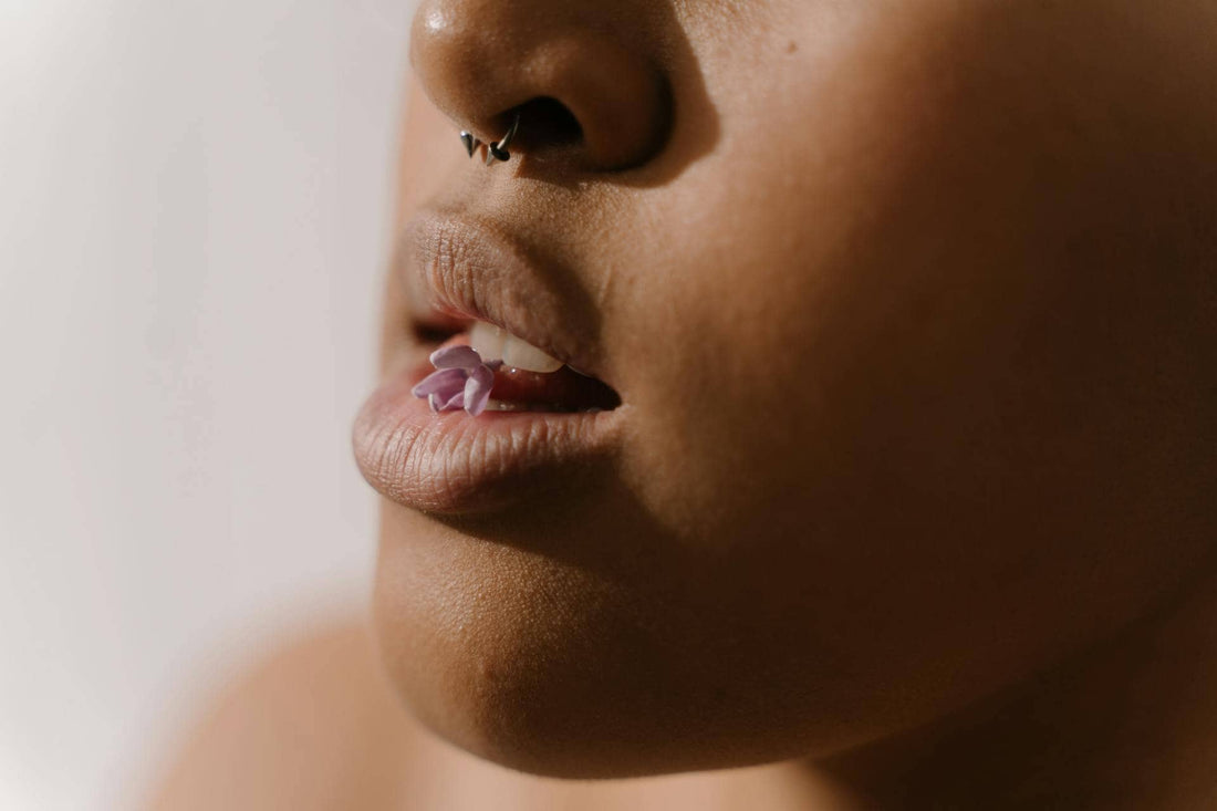 femme ayant un piercing et une fleur dans la bouche